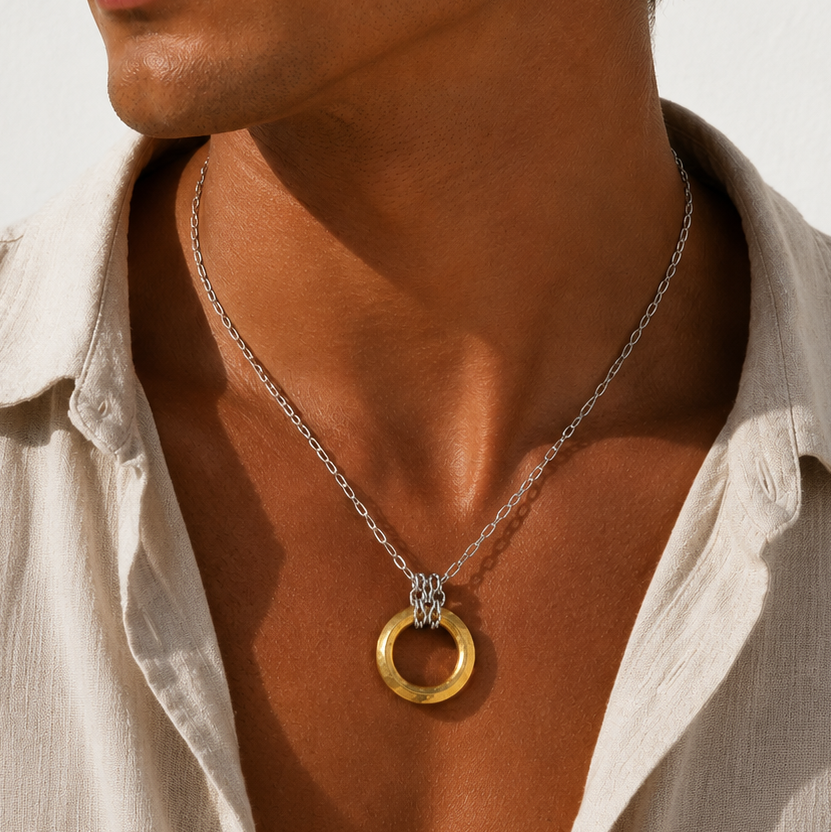 Man wearing a necklace with a gold pendant against a neutral background